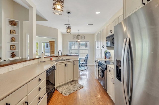 kitchen featuring black appliances, light wood finished floors, a sink, and light countertops