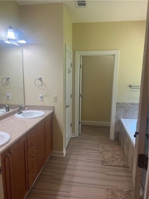 116 Bartram Trl, Blackshear, GA 31516 - full bathroom with wood finished floors, double vanity, tiled tub, and baseboards