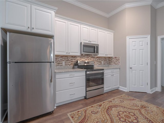 kitchen with stainless steel appliances, white cabinetry, and ornamental molding