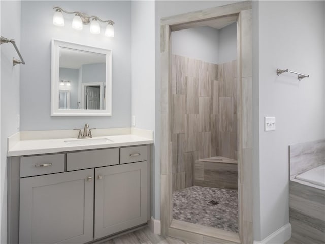 bathroom with a tile shower and vanity