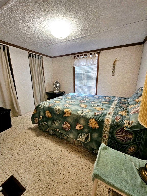 carpeted bedroom with a textured ceiling and ornamental molding