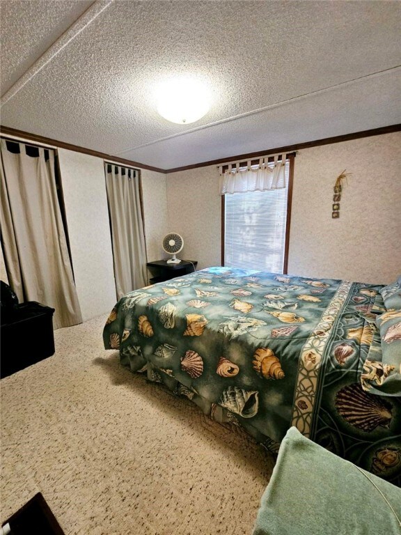 carpeted bedroom featuring crown molding and a textured ceiling