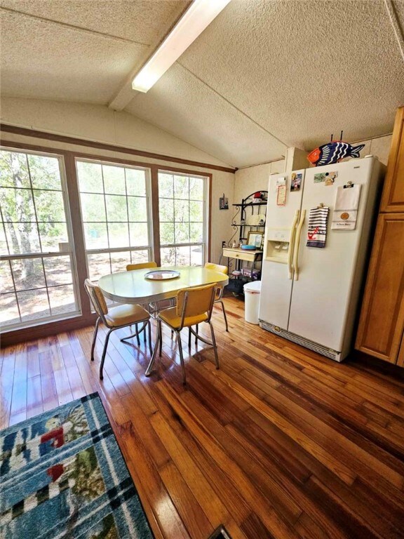 dining room featuring a textured ceiling, dark hardwood / wood-style flooring, and lofted ceiling