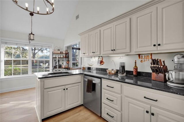 kitchen featuring stainless steel dishwasher, vaulted ceiling, sink, decorative light fixtures, and white cabinets