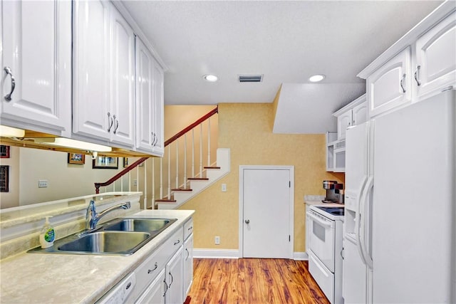 kitchen with sink, white appliances, light hardwood / wood-style floors, and white cabinets