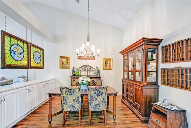 dining area featuring hardwood / wood-style flooring, lofted ceiling, and a chandelier