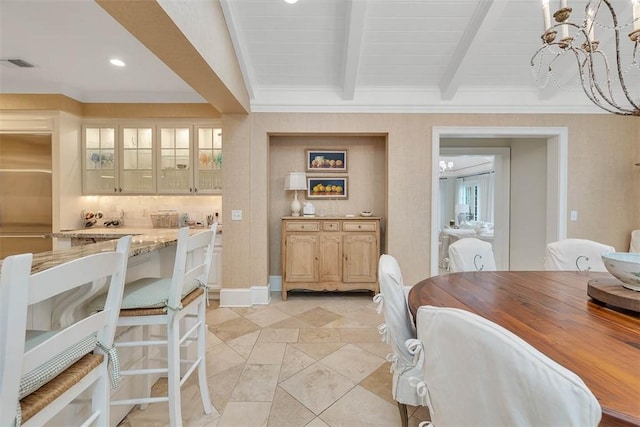 dining space with beam ceiling, a notable chandelier, visible vents, ornamental molding, and baseboards