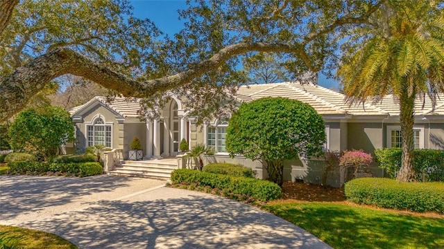 obstructed view of property featuring stucco siding and a tiled roof