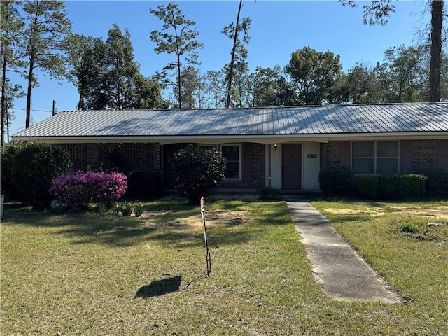 ranch-style house featuring metal roof, brick siding, and a front lawn