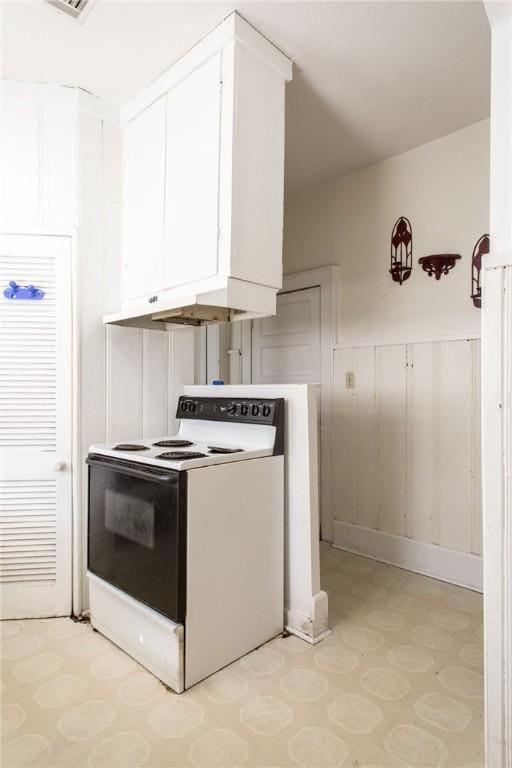 1006 Roosevelt St, Waycross, GA 31503 - kitchen featuring electric range, light flooring, a decorative wall, white cabinetry, and a wainscoted wall