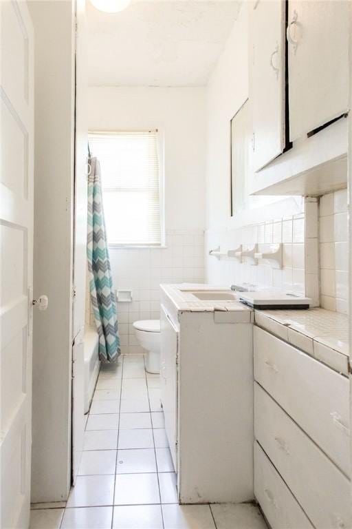 1006 Roosevelt St, Waycross, GA 31503 - bathroom featuring toilet, tile patterned floors, vanity, tile walls, and shower / tub combo with curtain