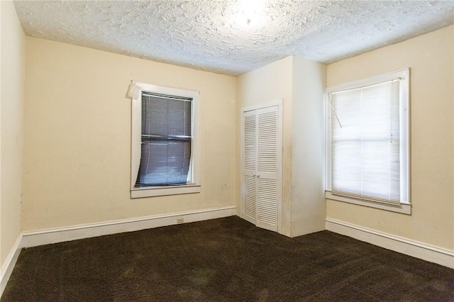 1006 Roosevelt St, Waycross, GA 31503 - unfurnished bedroom featuring dark colored carpet, a closet, a textured ceiling, and baseboards