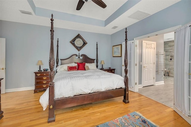 189 Harbor Pointe Dr, Brunswick, GA 31523 - bedroom with a raised ceiling, baseboards, light wood-style flooring, ceiling fan, and connected bathroom