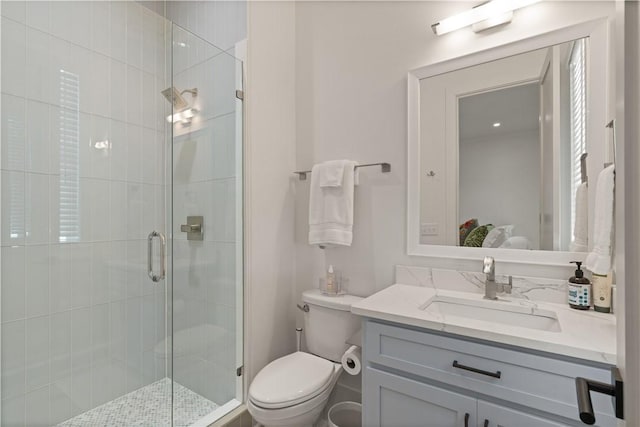 bathroom with vanity, a shower with shower door, and toilet