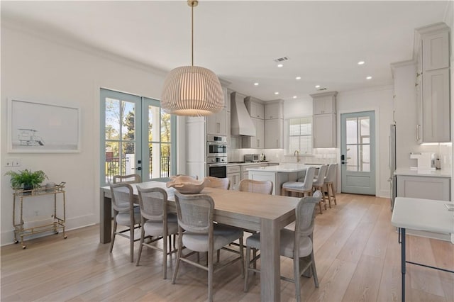 dining area with light hardwood / wood-style floors, ornamental molding, and sink