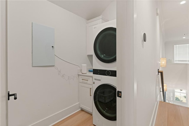 laundry room featuring plenty of natural light, light hardwood / wood-style floors, and stacked washer and dryer