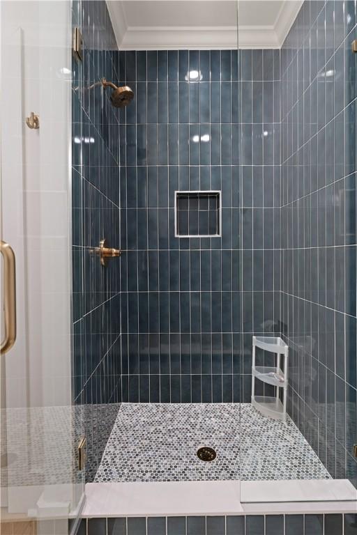 bathroom featuring a shower with shower door and crown molding