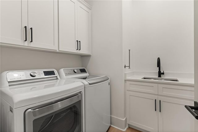 laundry area featuring washer and clothes dryer, sink, and cabinets