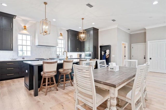 dining room with crown molding, sink, and light hardwood / wood-style floors