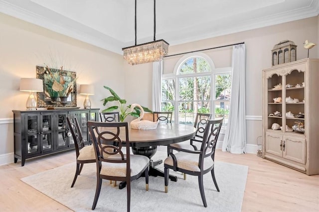 dining room with light hardwood / wood-style floors, an inviting chandelier, and ornamental molding