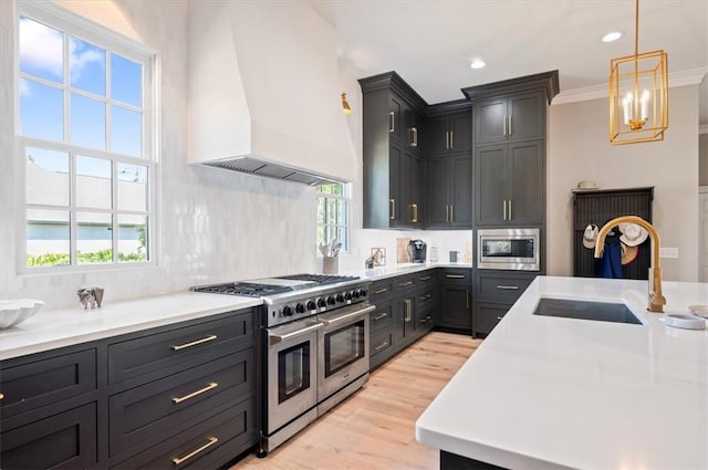 kitchen featuring ornamental molding, custom range hood, stainless steel appliances, sink, and decorative light fixtures