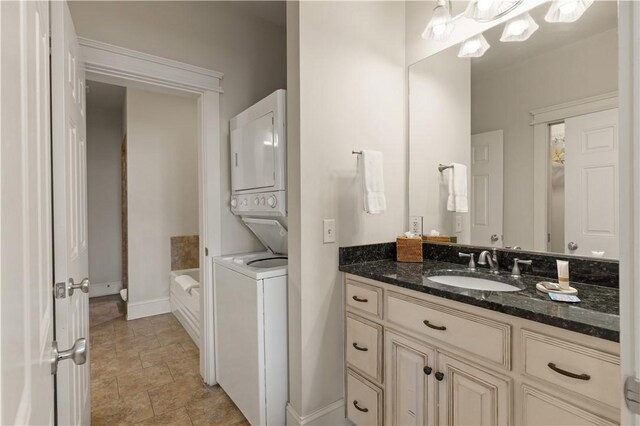 bathroom with vanity, a washtub, and stacked washer and clothes dryer