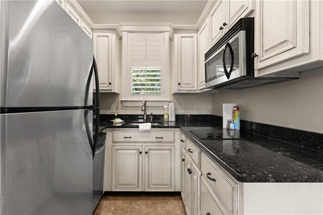 kitchen with white cabinets, stainless steel appliances, dark stone countertops, and sink