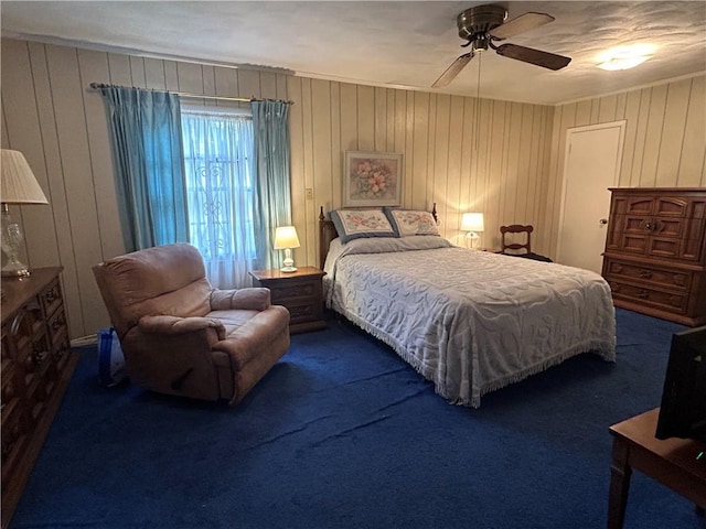 bedroom featuring ceiling fan, wooden walls, and carpet