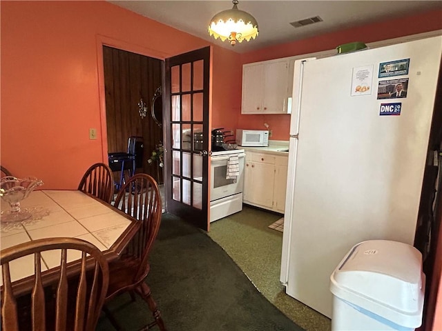 kitchen with white cabinets, hanging light fixtures, white appliances, and dark carpet