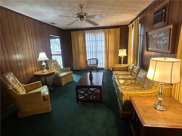 sitting room with wooden walls, ceiling fan, and dark colored carpet