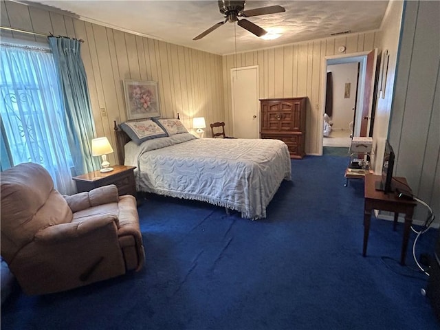 bedroom with ceiling fan, dark carpet, and wooden walls