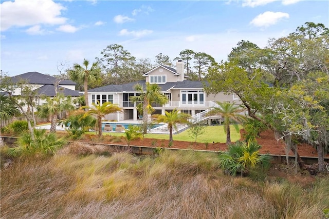 rear view of property with an outdoor pool and a chimney