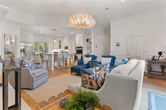 living room featuring ornamental molding, recessed lighting, a chandelier, and light wood-style flooring