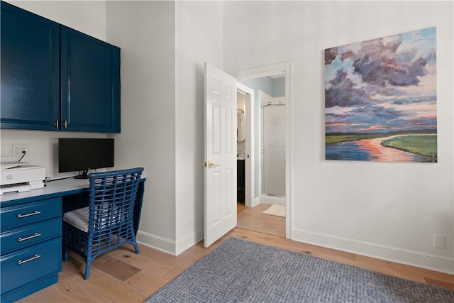 office featuring baseboards, light wood-type flooring, and built in desk
