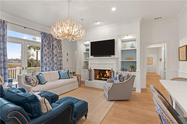 living room with visible vents, built in features, a brick fireplace, light wood finished floors, and crown molding