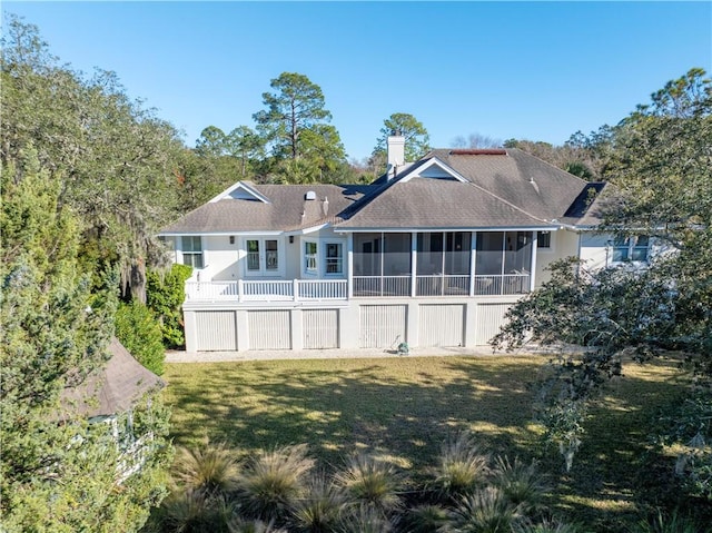 rear view of house featuring a lawn and a sunroom