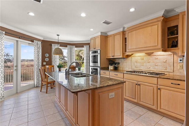 kitchen with sink, stainless steel appliances, an island with sink, and dark stone counters