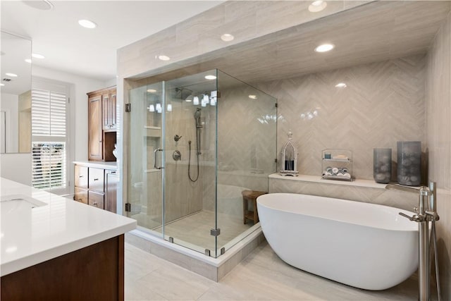 bathroom featuring independent shower and bath, vanity, and tile walls