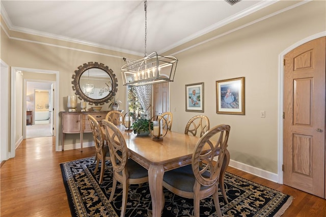 dining area featuring hardwood / wood-style flooring, ornamental molding, and an inviting chandelier