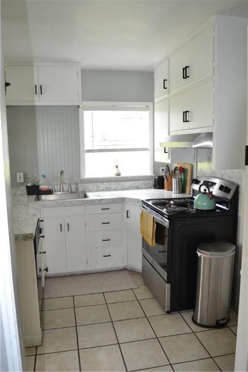 1308 Dean Dr, Waycross, GA 31501 - kitchen with stainless steel electric stove, extractor fan, light tile patterned flooring, light countertops, and white cabinetry