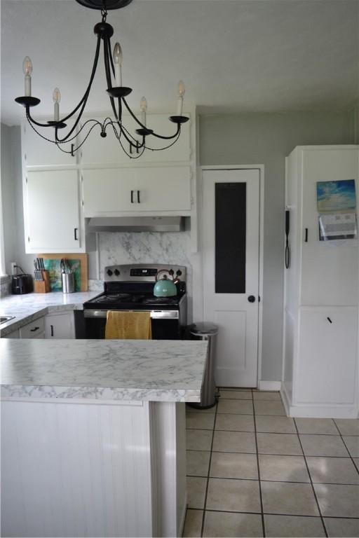 1308 Dean Dr, Waycross, GA 31501 - kitchen featuring stainless steel range with electric cooktop, ventilation hood, light tile patterned flooring, light countertops, and white cabinets