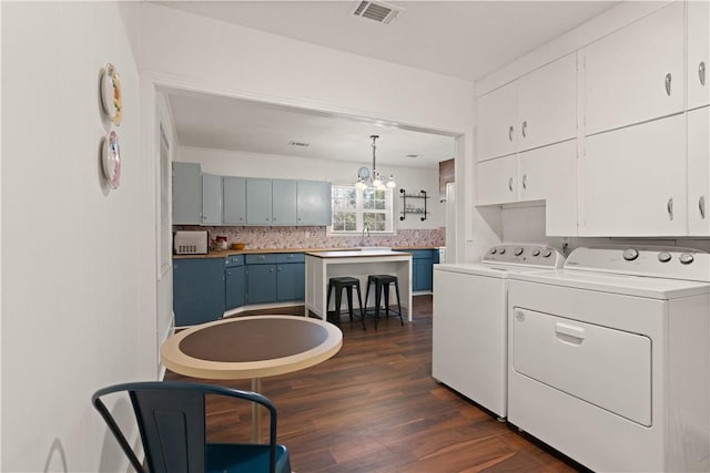 kitchen with dark wood-type flooring, blue cabinets, white cabinetry, separate washer and dryer, and hanging light fixtures