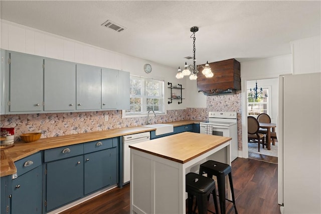 kitchen featuring butcher block countertops, a center island, and white appliances