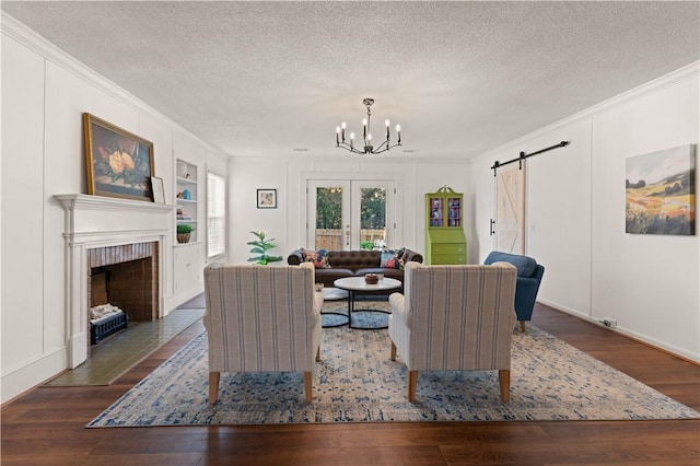 living room featuring crown molding, a textured ceiling, dark hardwood / wood-style flooring, built in features, and a barn door