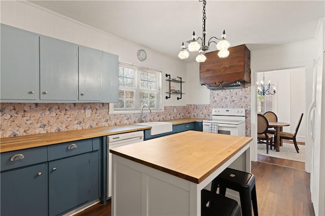 kitchen featuring a kitchen island, sink, wooden counters, a notable chandelier, and white appliances