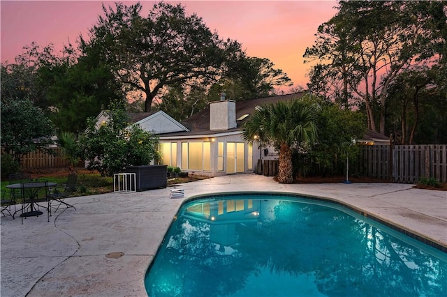 pool at dusk featuring a patio