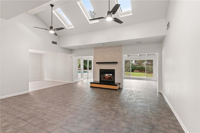 unfurnished living room with ceiling fan, a fireplace, high vaulted ceiling, and a skylight