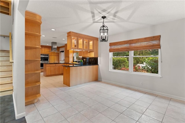 kitchen featuring kitchen peninsula, wall chimney exhaust hood, double oven, light tile patterned floors, and decorative light fixtures