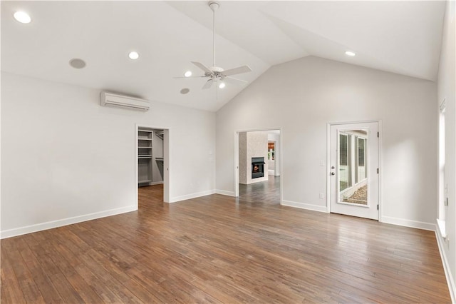 unfurnished living room featuring a wall unit AC, ceiling fan, dark wood-type flooring, high vaulted ceiling, and a fireplace