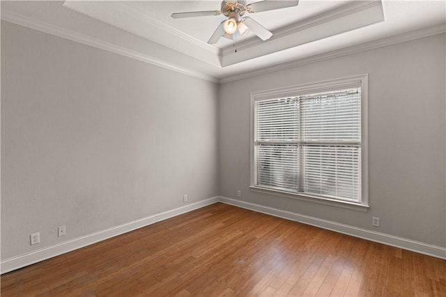 unfurnished room with hardwood / wood-style flooring, ceiling fan, ornamental molding, and a tray ceiling